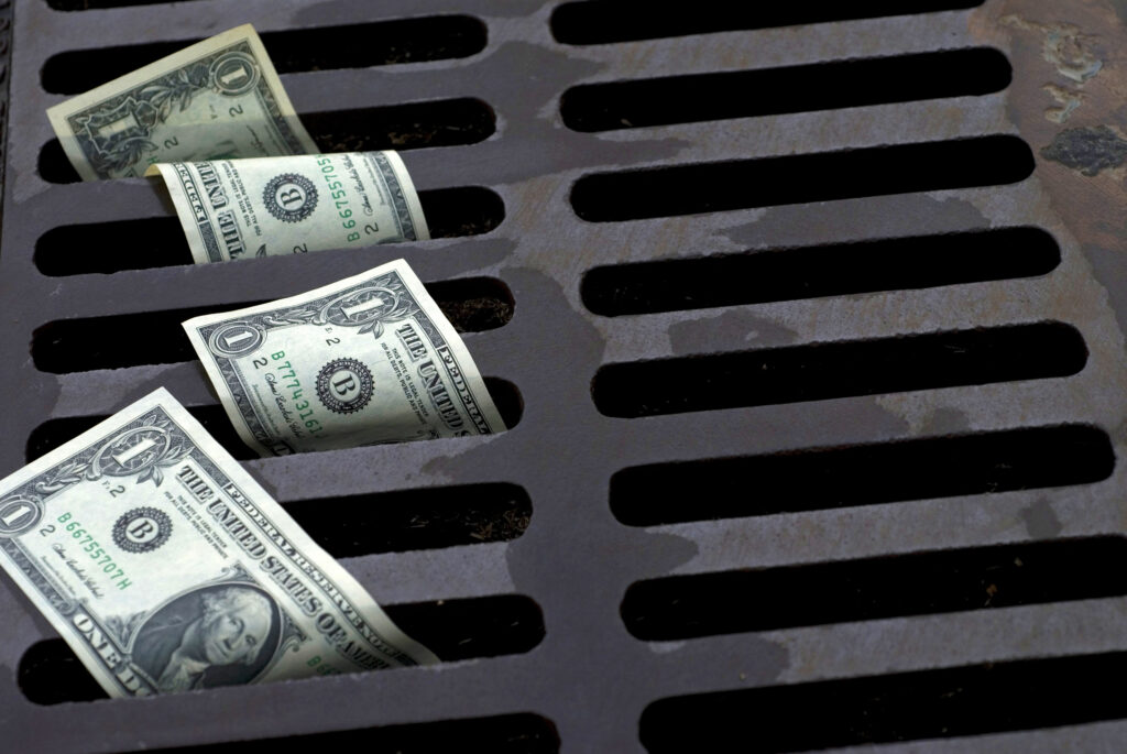 US Dollar bills down the street drain