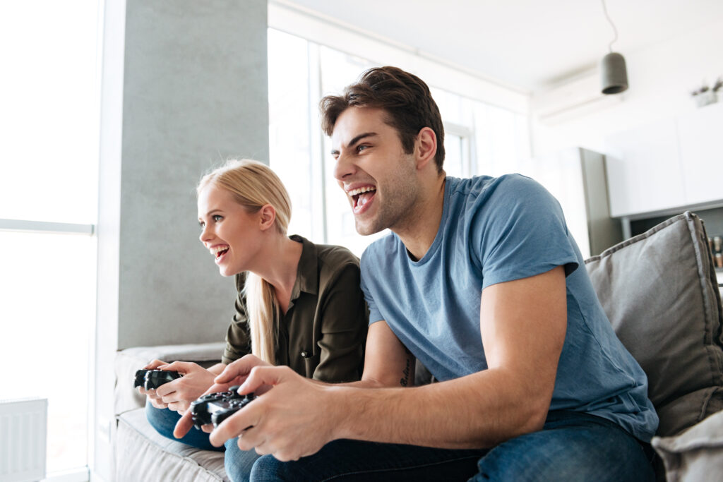 Young gambled concentrated lovers playing video games at home in living room